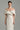 White taffeta column gown with sculpted off-shoulder draping and crystal embellishments - IHF STUDIO