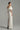 White taffeta column gown with sculpted off-shoulder draping and crystal embellishments - IHF STUDIO